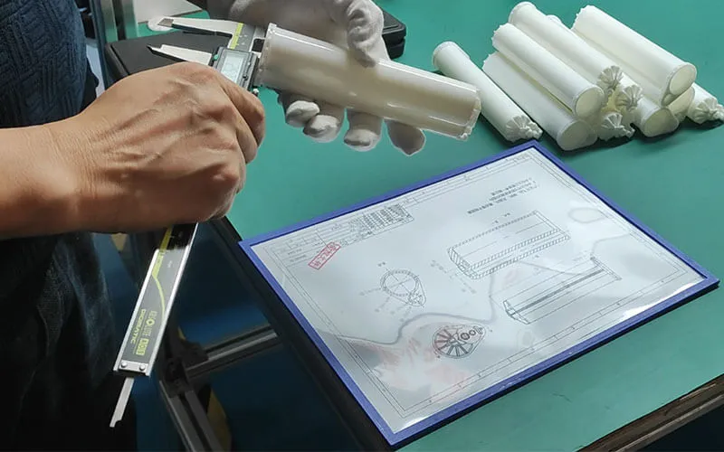 Worker uses caliper to inspect dimension of dual glue cartridge, factory quality control inspection with technical drawing